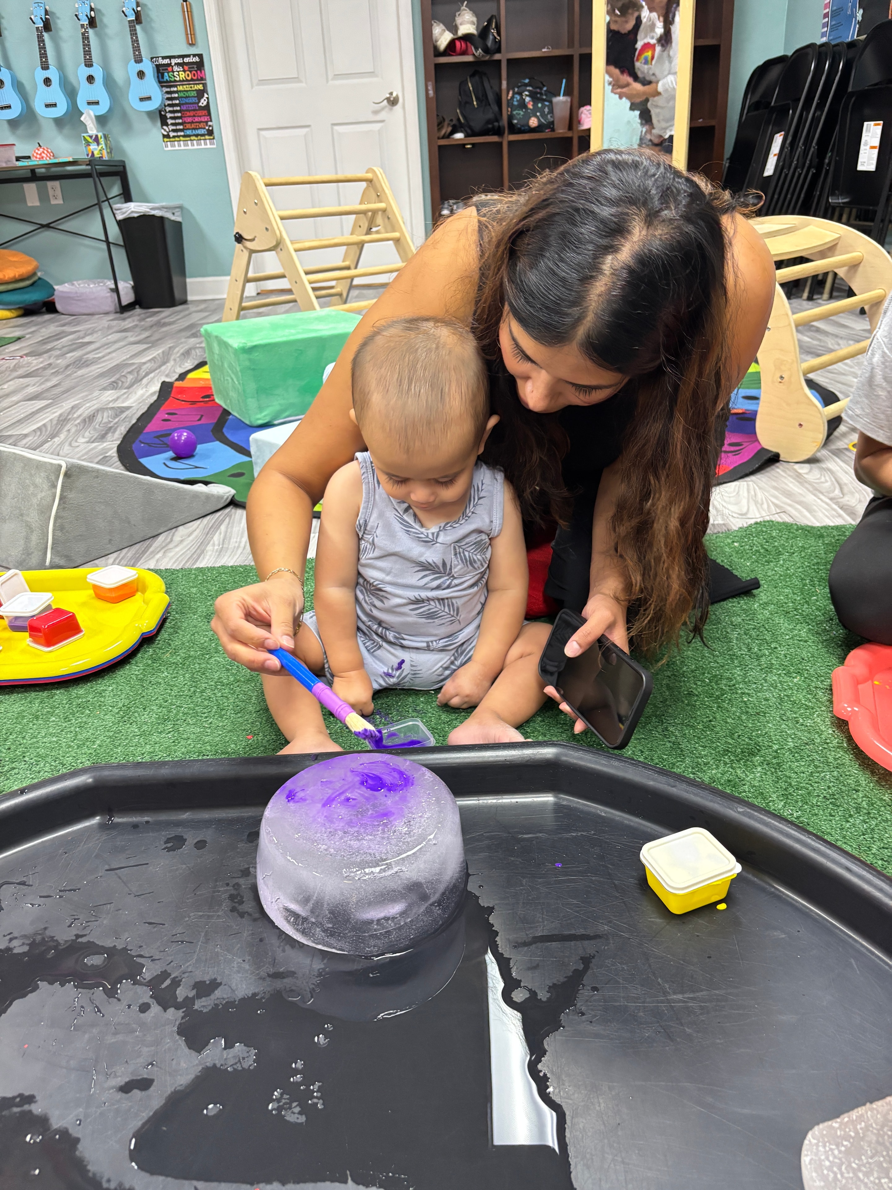Kids exploring a dinosaur sensory bin with green gel beads